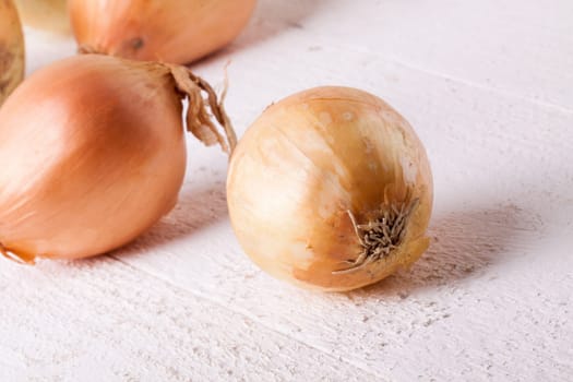 Fresh onions with brown peel on a rustic wooden board as close-up
