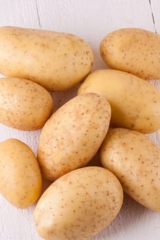 Fresh washed potatoes with peel as a close-up on a rustic wooden board
