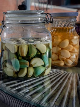Glass jars with Garlic pickled in Apple cider vinegar with Rock sugar. Healthy pickled green and yellow garlic, Garlic cooking, Space for text, Selective focus.