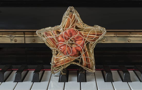 Golden star shaped mesh case is filled with dried fruits stand on the Piano Keyboard. Dried fruits in star shaped metal case on keyboard, Christmas decoration, Success concept, Space for text, Selective focus.