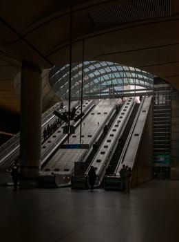 London, England - Oct 16, 2023 - People riding the escalators inside of the Canary Wharf underground tube station. It is a station on the Jubilee Line, between Canada Water and North Greenwich, Copy space, Selective focus.