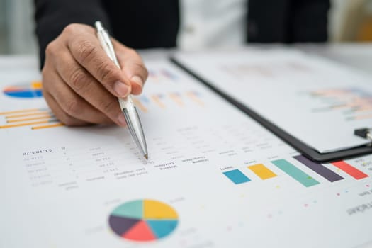 Asian accountant working and analyzing financial reports project accounting with chart graph in  office, finance and business.