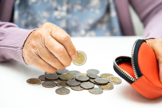 Asian senior woman holding counting coin money in purse. Poverty, saving problem in retirement.