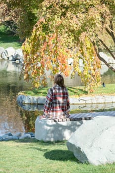 Woman in red plaid shirt enjoying nature standing in Japanese Garden