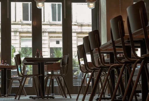Liverpool, England - Oct 07, 2023 - Beautiful design inside of Restaurant. Decorated with wooden table with chairs next to glass doors. Space for text, Selective focus.