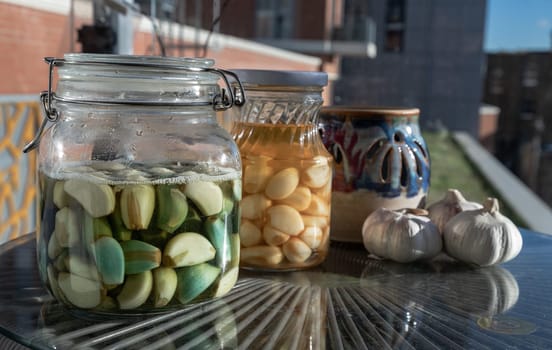 Glass jars with Garlic pickled in Apple cider vinegar with Rock sugar. Healthy pickled green and yellow garlic, Garlic cooking, Space for text, Selective focus.