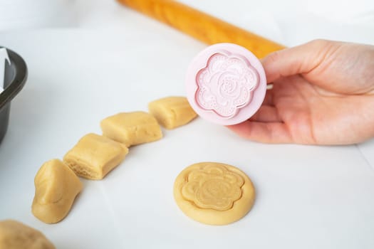 The process of making cookies with shapes in the form of flowers, a rolling pin and a tray, the concept of cooking, baking at home