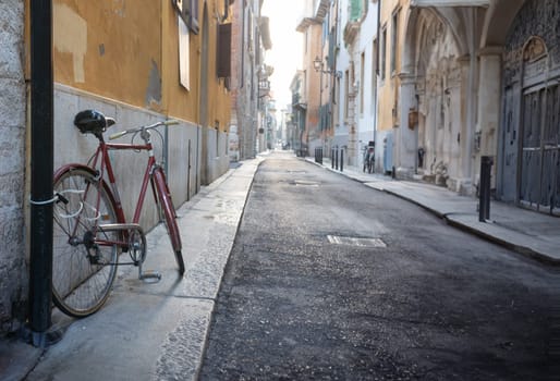 A quiet, narrow street, showcasing old architecture and a lone parked bicycle.
