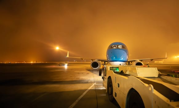 Airport transporter moves airplane on the runway at night - aircrafrt