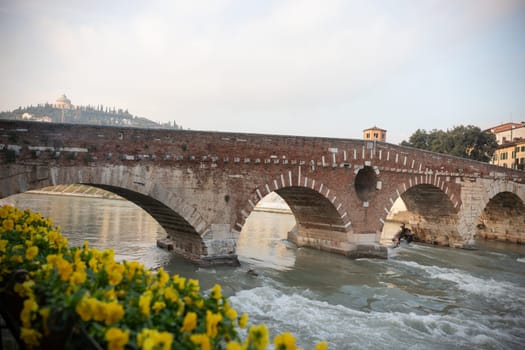 An arched bridge over flowing water - italian medieval landscape, Verona