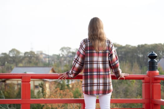 back view of unrecognizable Woman in red plaid shirt enjoying nature walking in Japanese Garden with red pagoda