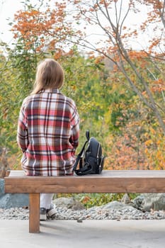 Woman in red plaid shirt enjoying nature sitting in Japanese Garden