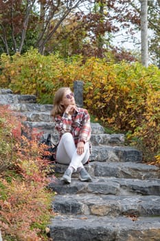 Woman in red plaid shirt enjoying nature sitting in Japanese Garden