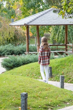 Woman in red plaid shirt enjoying nature sitting in Japanese Garden