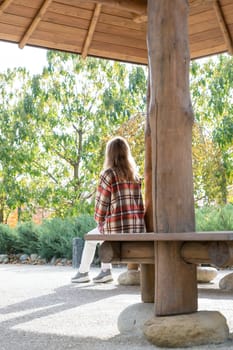 Woman in red plaid shirt enjoying nature sitting in Japanese Garden