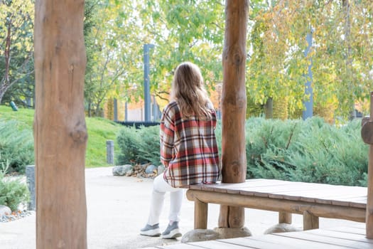 Woman in red plaid shirt enjoying nature sitting in Japanese Garden