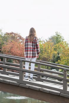 Woman in red plaid shirt enjoying nature sitting in Japanese Garden