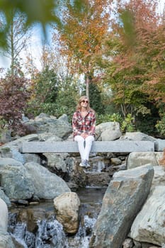 Woman in red plaid shirt enjoying nature sitting in Japanese Garden