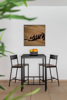 Black table with chairs and fruit bowl in home dining area. Stylish place to take food in renovated apartment interior. Design ideas