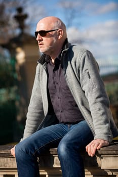Trendy senior man with sporty clothes relaxes in the outdoors in the sun
