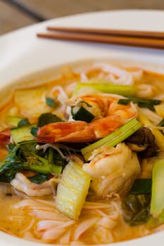 Bowl plate with freshly prepared Tom Yam soup with clanguste and coriander with chopsticks as close-up