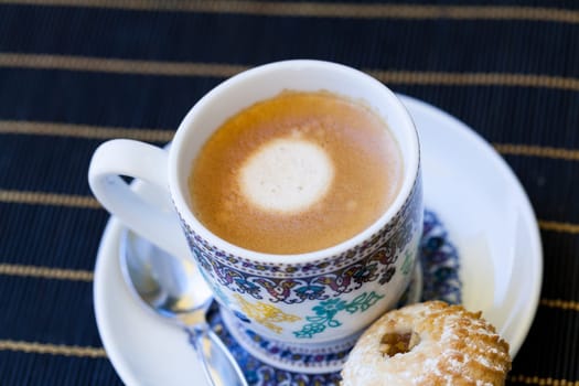 Cup with fresh coffee espresso coffee spoon and pastries as close-up