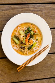 Bowl plate with freshly prepared Tom Yam soup with clanguste and coriander with chopsticks as close-up