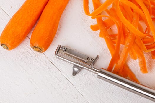 Fresh orange carrots beet turn beets peeled with peelers and bowls on a white wooden board