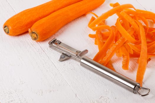 Fresh orange carrots beet turn beets peeled with peelers and bowls on a white wooden board