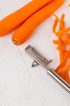 Fresh orange carrots beet turn beets peeled with peelers and bowls on a white wooden board