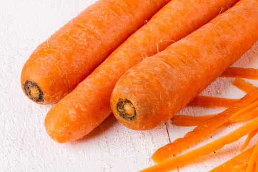 Fresh orange carrots beet turn beets peeled with peelers and bowls on a white wooden board