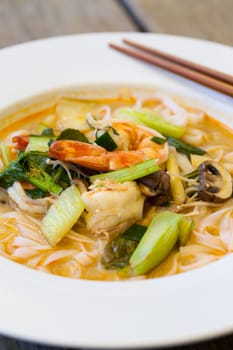 Bowl plate with freshly prepared Tom Yam soup with clanguste and coriander with chopsticks as close-up