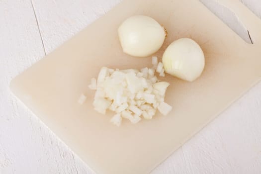White and red onions peeled and with slurs as a whole and in cubebrunoise as a close-up on cutting board