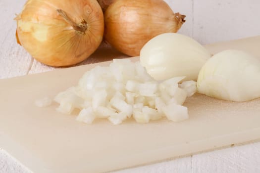 White and red onions peeled and with slurs as a whole and in cubebrunoise as a close-up on cutting board