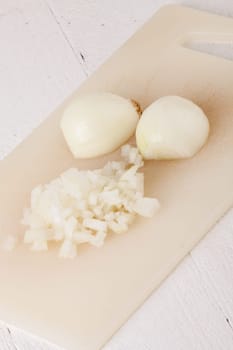 White and red onions peeled and with slurs as a whole and in cubebrunoise as a close-up on cutting board
