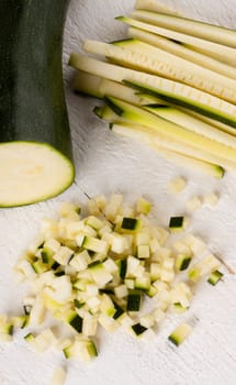 Fresh zucchini all in julienne strips and cut into brunoise cubes on a white hoözboard