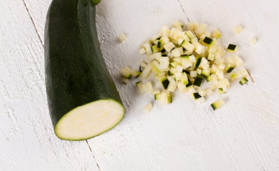 Fresh zucchini all in julienne strips and cut into brunoise cubes on a white hoözboard