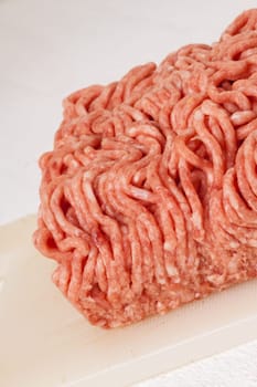 Minced meat raw beef and pork mixed as a block of protective atmosphere as a close-up on a white plate