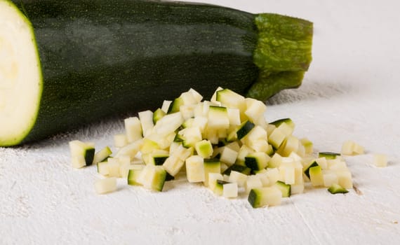 Fresh zucchini all in julienne strips and cut into brunoise cubes on a white hoözboard