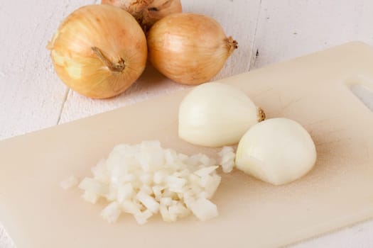 White and red onions peeled and with slurs as a whole and in cubebrunoise as a close-up on cutting board