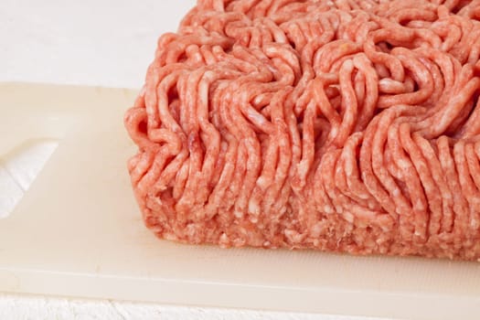 Minced meat raw beef and pork mixed as a block of protective atmosphere as a close-up on a white plate