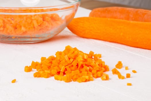 Fresh carrots beet root beet as whole and finely diced brunoise in a bowl on a white wooden board