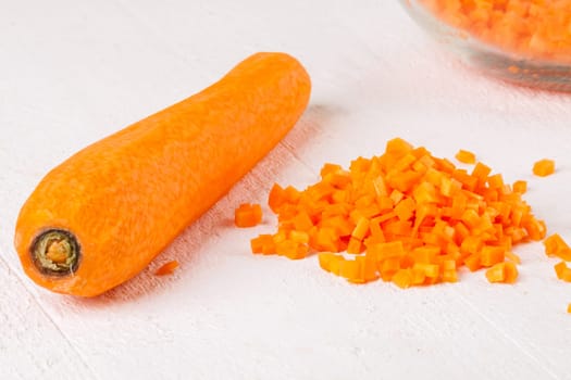 Fresh carrots beet root beet as whole and finely diced brunoise in a bowl on a white wooden board