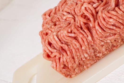 Minced meat raw beef and pork mixed as a block of protective atmosphere as a close-up on a white plate