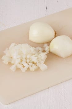 White and red onions peeled and with slurs as a whole and in cubebrunoise as a close-up on cutting board