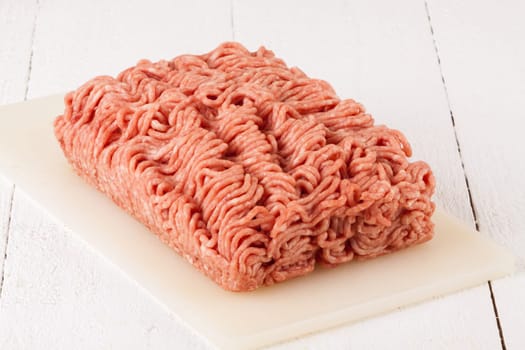 Minced meat raw beef and pork mixed as a block of protective atmosphere as a close-up on a white plate