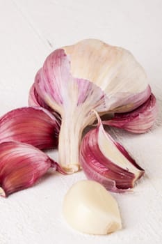 Garlic tuber with toes Fresh in whole and as a detail as a close-up on white wood