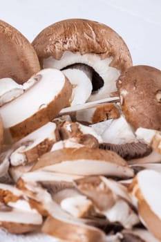 Fresh stone mushrooms Champiggnons whole and sliced on a white wooden board
