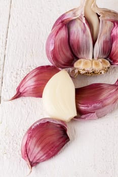 Garlic tuber with toes Fresh in whole and as a detail as a close-up on white wood