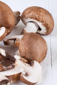 Fresh stone mushrooms Champiggnons whole and sliced on a white wooden board